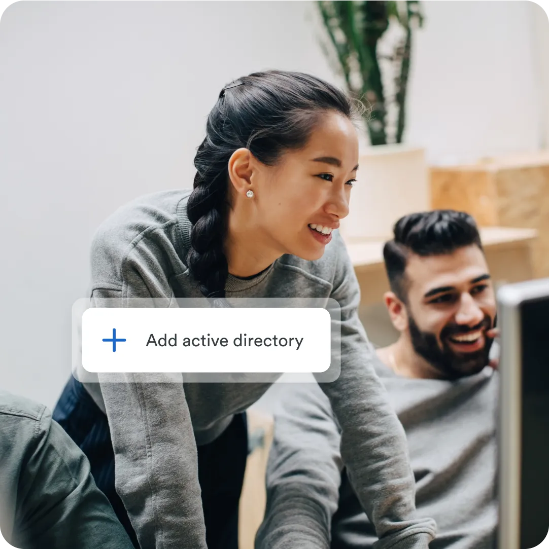 Two professionals looking at a desktop monitor for Duo Essentials with flexible deployment options including Active Directory sync.