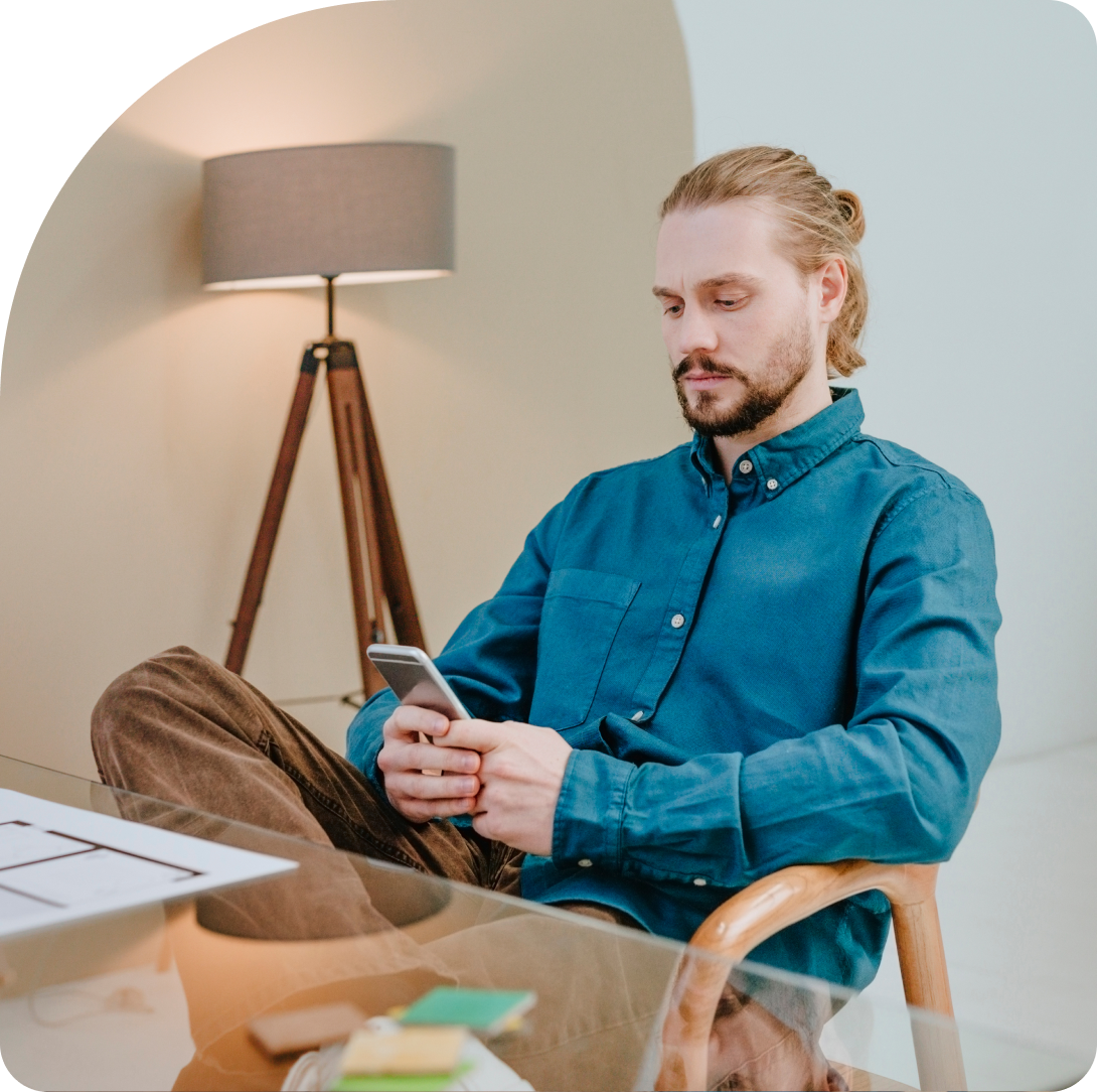 Professional sitting with their leg crossed at their desk, looking down at the Duo learning hub on their mobile device