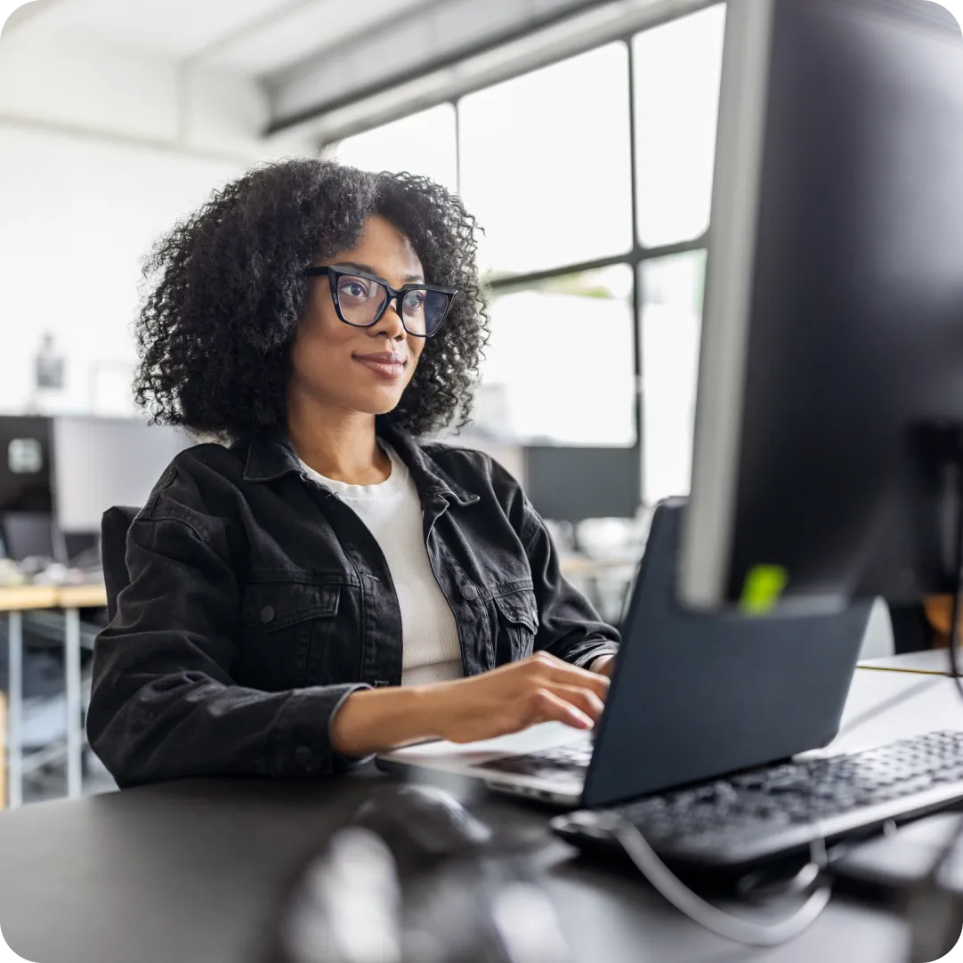 Professional sitting at their desk with glasses on and their laptop in front of them, showing interest in Duo's MSP Program to grow their business.