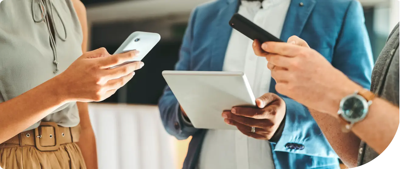 Group of three people using a tablet and smartphones together.