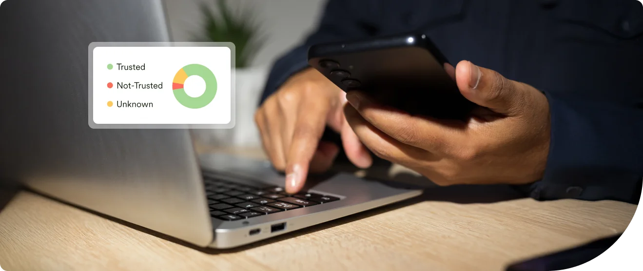 Person using a smartphone and laptop at a desk, with an on-screen graphic showing device trust levels labeled Trusted, Not Trusted, and Unknown