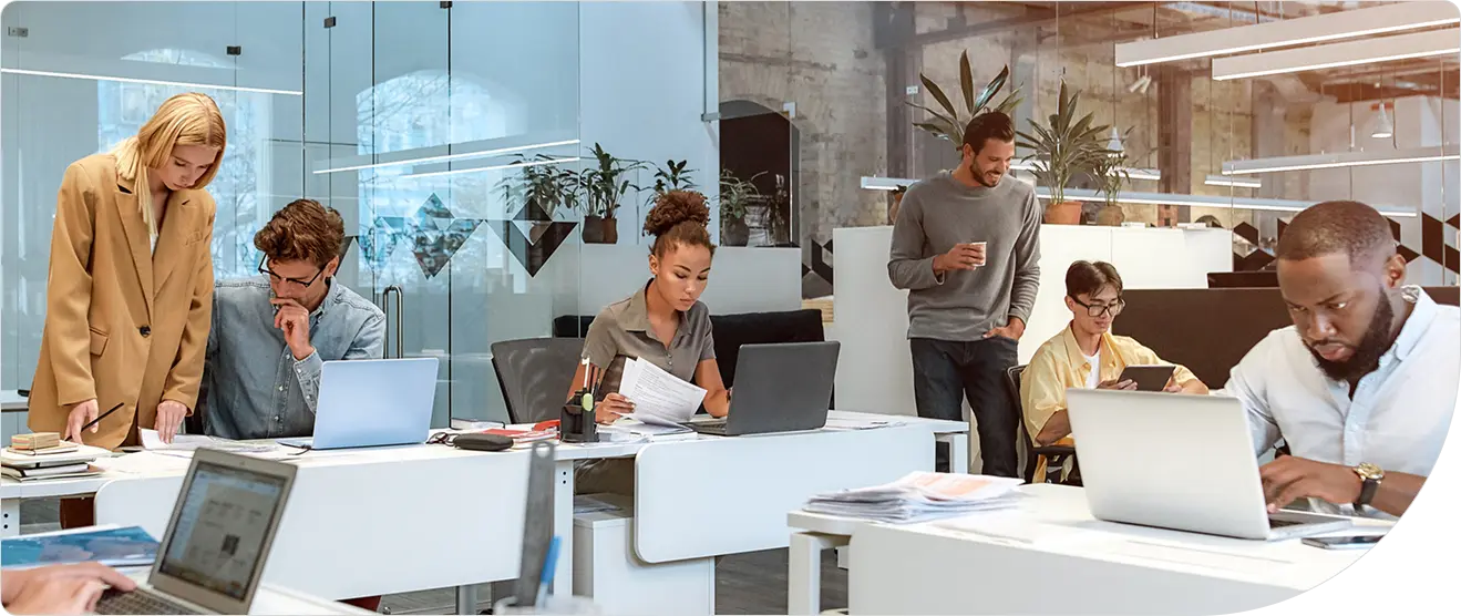 A team working at networked computer stations in a modern office, representing organizations deploying and managing agentic AI systems