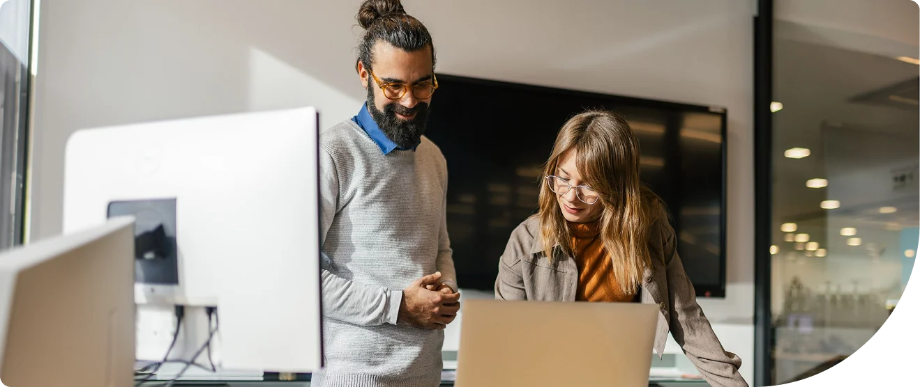 Two security professionals reviewing identity threat data together on a laptop in a modern office