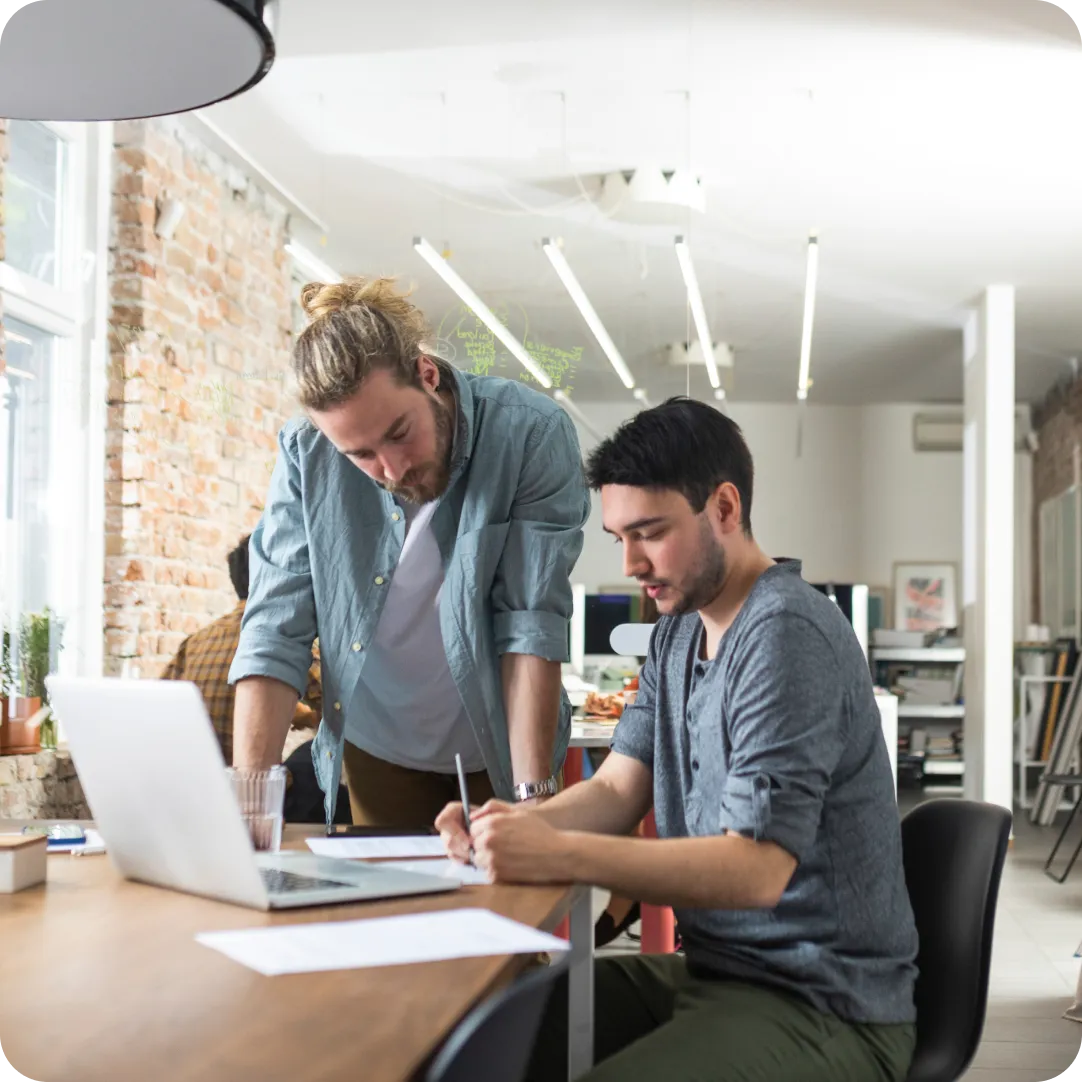 Two coworkers standing at a table reviewing the Duo plans to start their 30 day free trial with Duo Security.