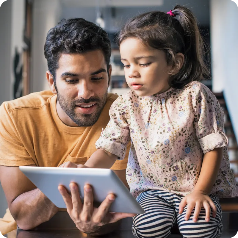 A school employee helps an elementary school child use a tablet, Duo helps their school meet security compliance.