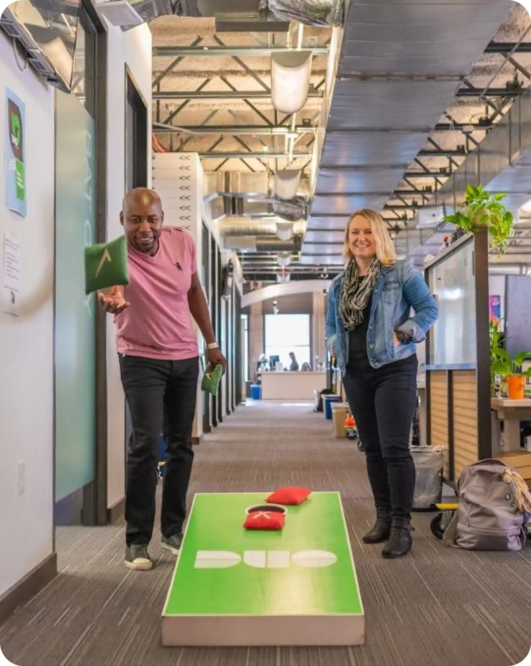 Two Duo employees playing a game of cornhole in the Duo office.